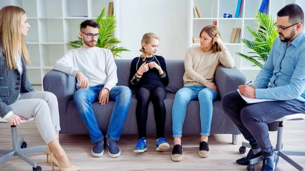 Family participating in therapy session addressing teen addiction and its impact on parents and siblings.