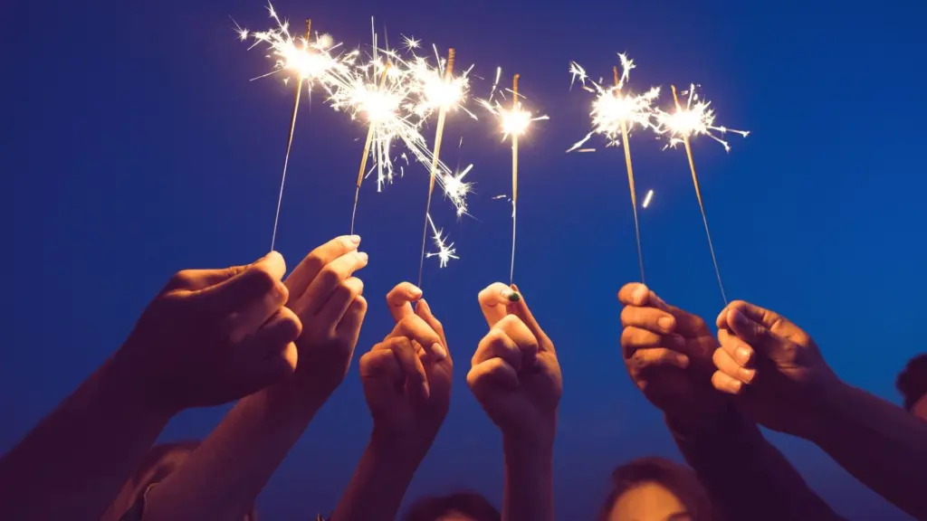 Group of teens holding sparklers at night, symbolizing risk-taking and vulnerability.