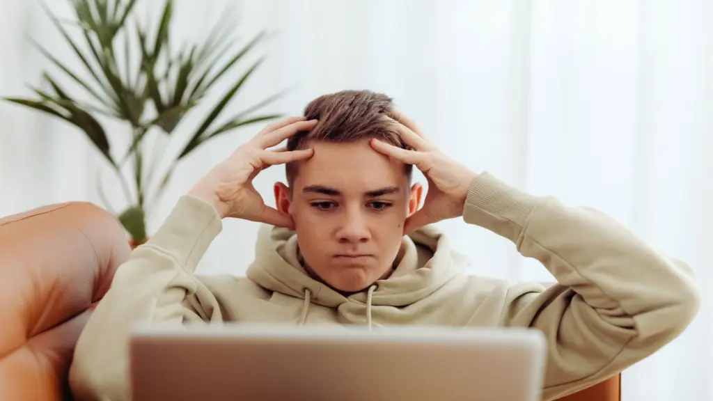 Teen showing stress and anxiety while using a laptop at home
