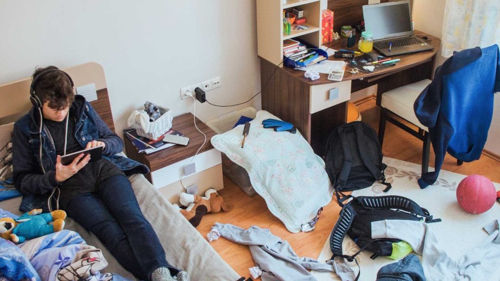 Teen boy isolating in a cluttered room, showing common signs of trauma.